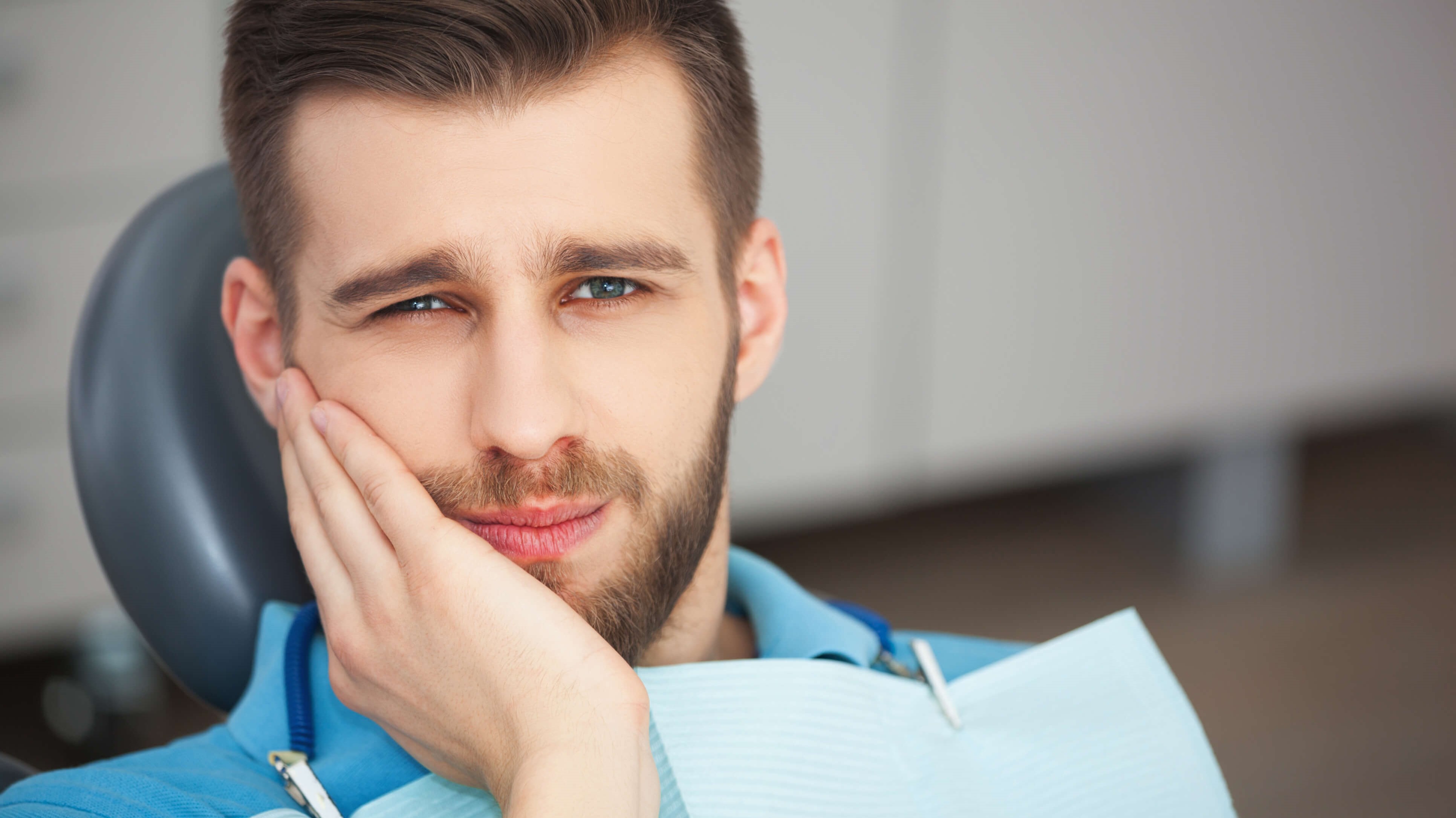 man holding jaw for tooth pain